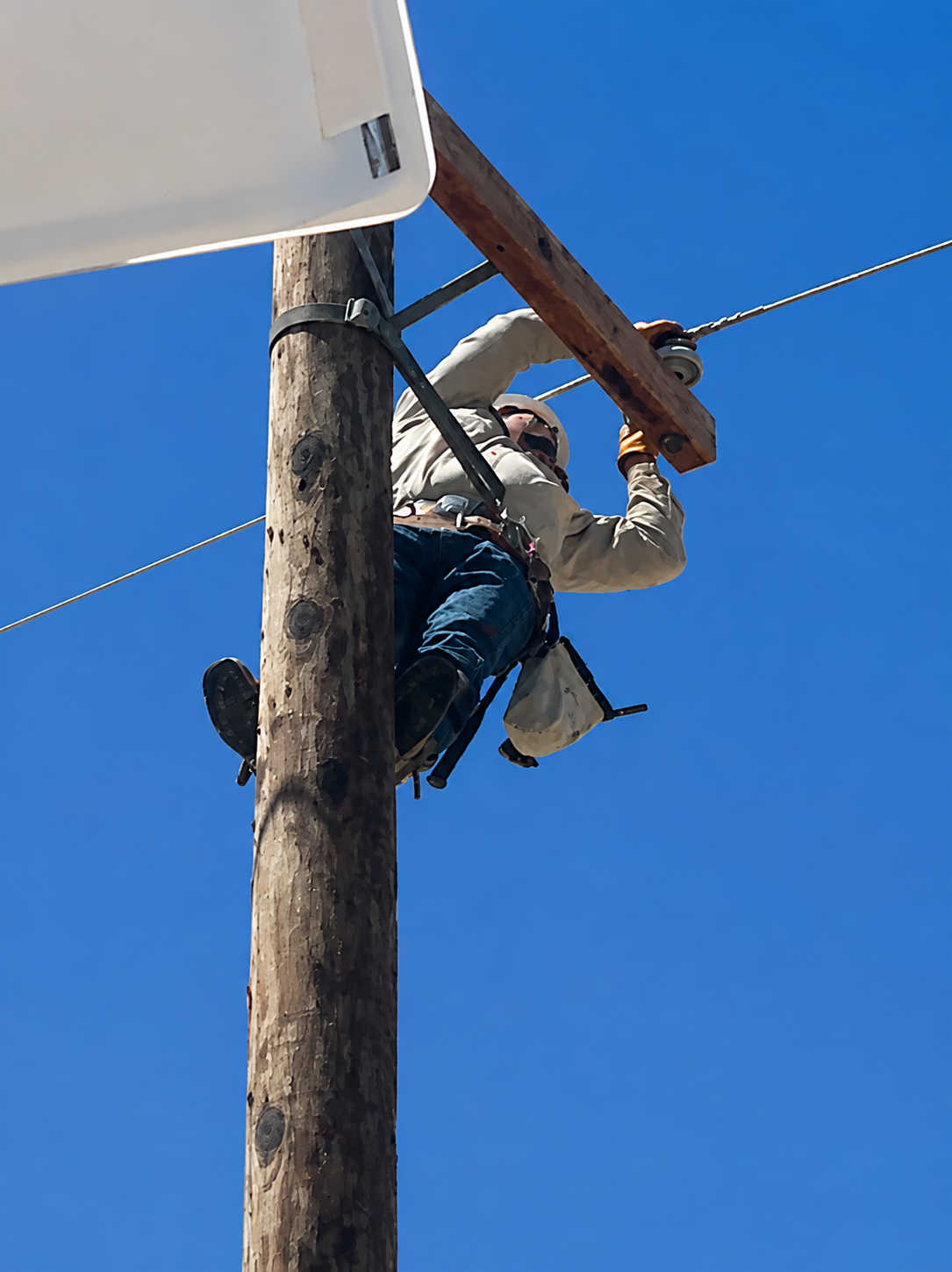 Lineman maintaining overhead electrical lines on a utility pole