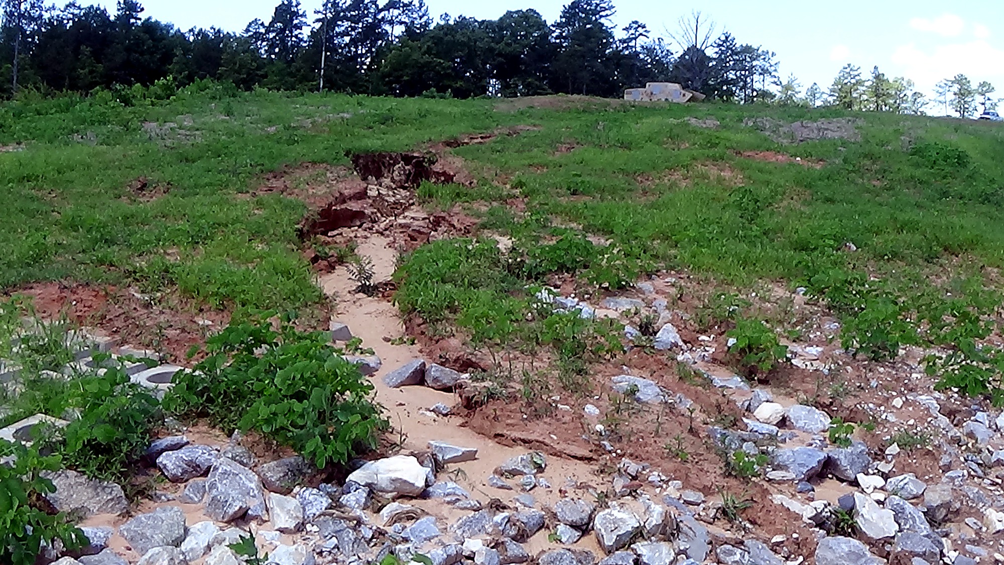 Erosion damage in a grassy drainage channel before restoration