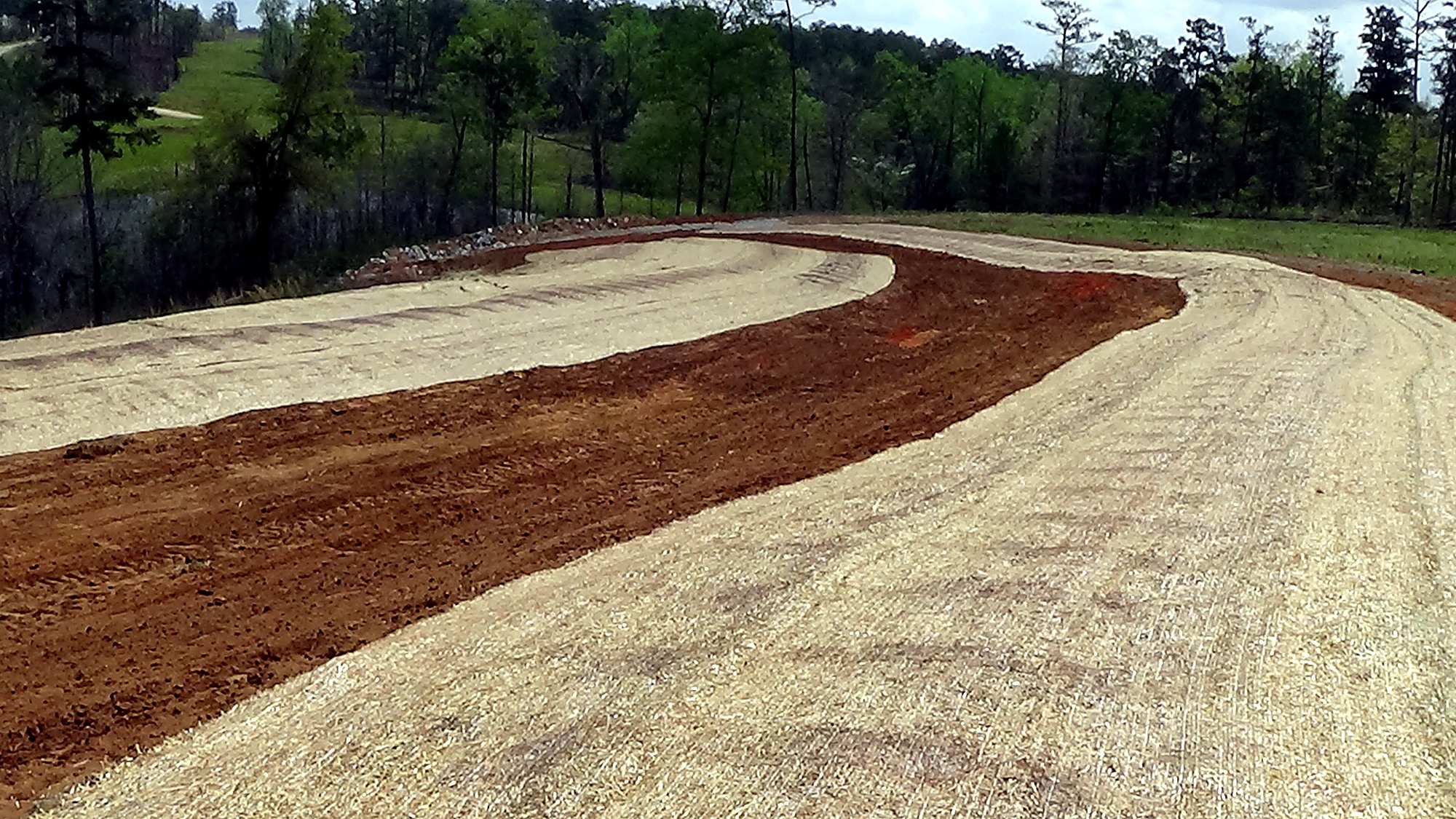 Completed gravel roadway and drainage repair beside wooded terrain
